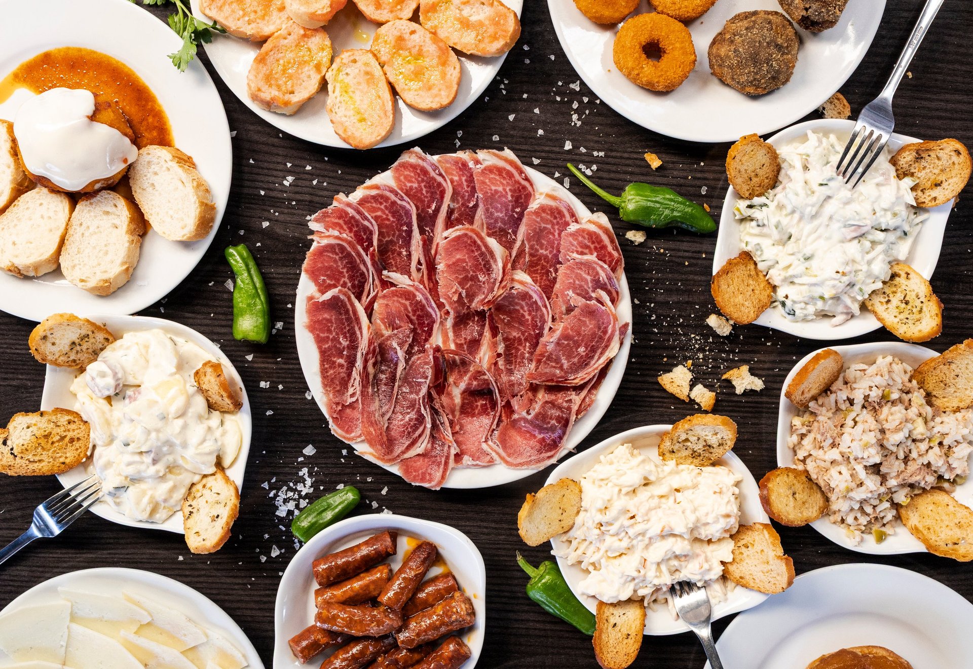 Assortment of spanish tapas with cured ham, chorizo, croquettes, alioli, and bread